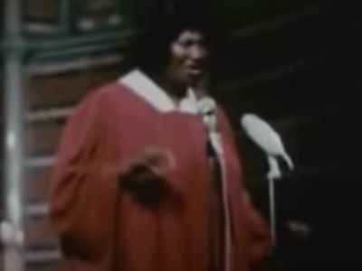 Mahalia Jackson is on stage, standing in front of a mic.